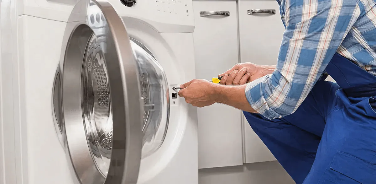 Handyman repairing a clothes dryer and checking electrical connections in Nashville, TN