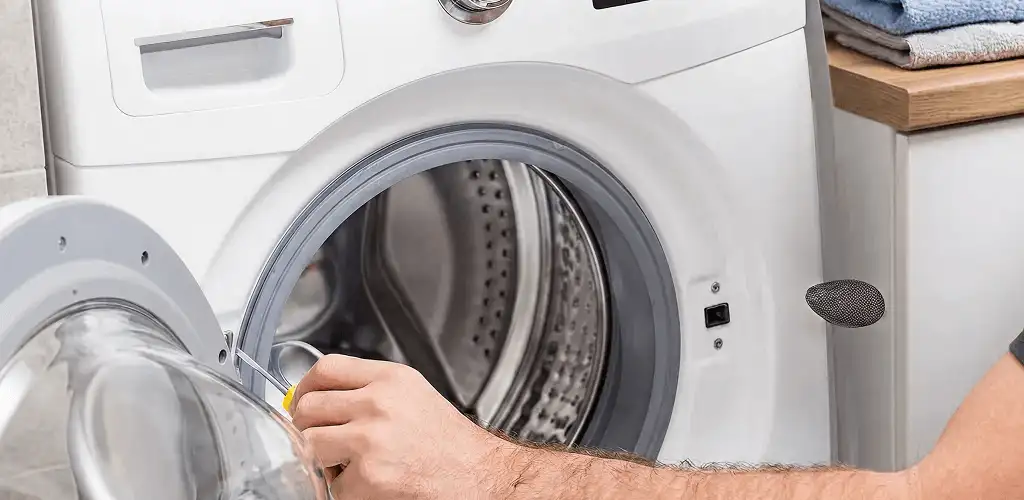 Handyman repairing a front-load washing machine and inspecting the drum in Nashville, TN